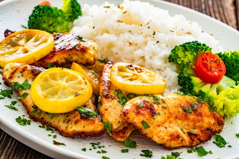 Lemon chicken escalopes with rice on wooden table